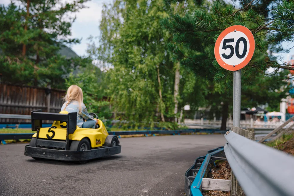 Ryggen av et barn so mkjører liten el-bil på en el-bilbane